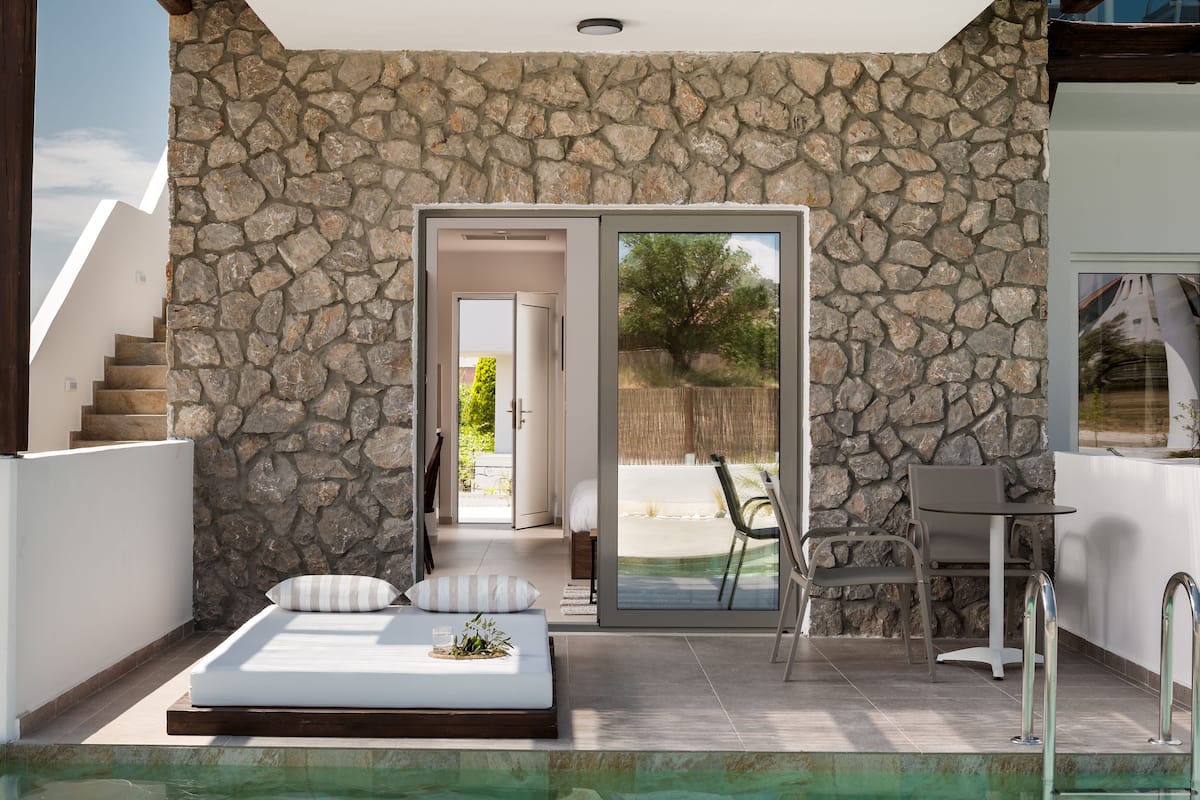 A bedroom with a stone wall, a bed, and an outdoor pool area.