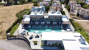 A modern building with a swimming pool, outdoor seating, and solar panels. - Nama Retreat (Rhodes)