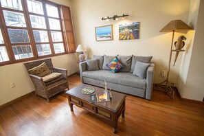 A living room with a grey sofa, wicker armchair, wooden coffee table, and a floor lamp.
