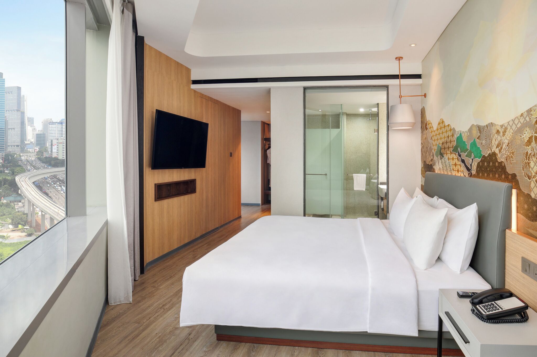 Habitación de hotel moderna con una cama grande, un televisor de pantalla plana, un escritorio con teléfono y vistas a la ciudad.