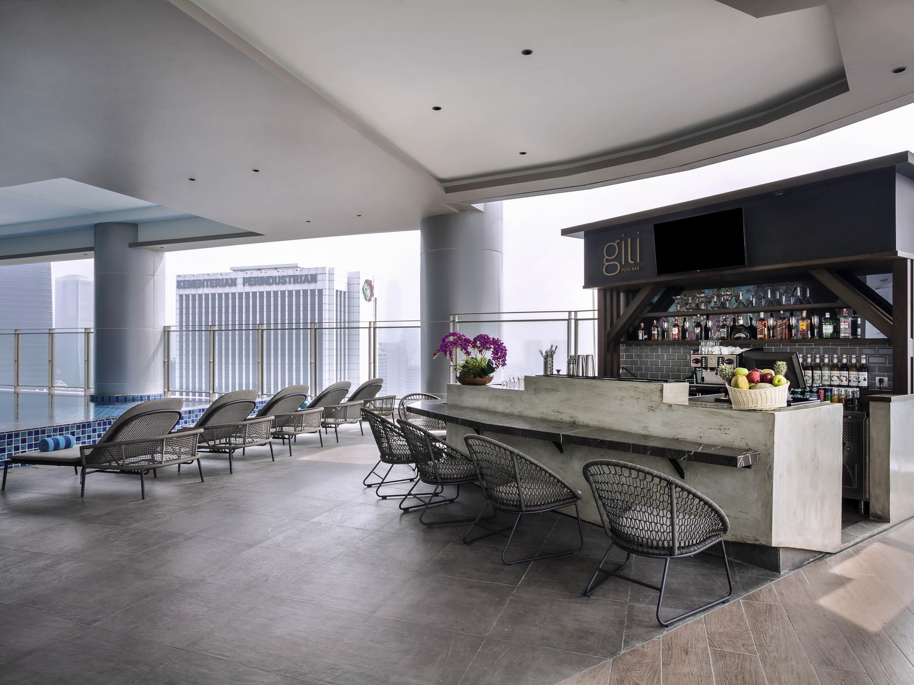 A rooftop bar with a bar counter, seating area, and a city view.
