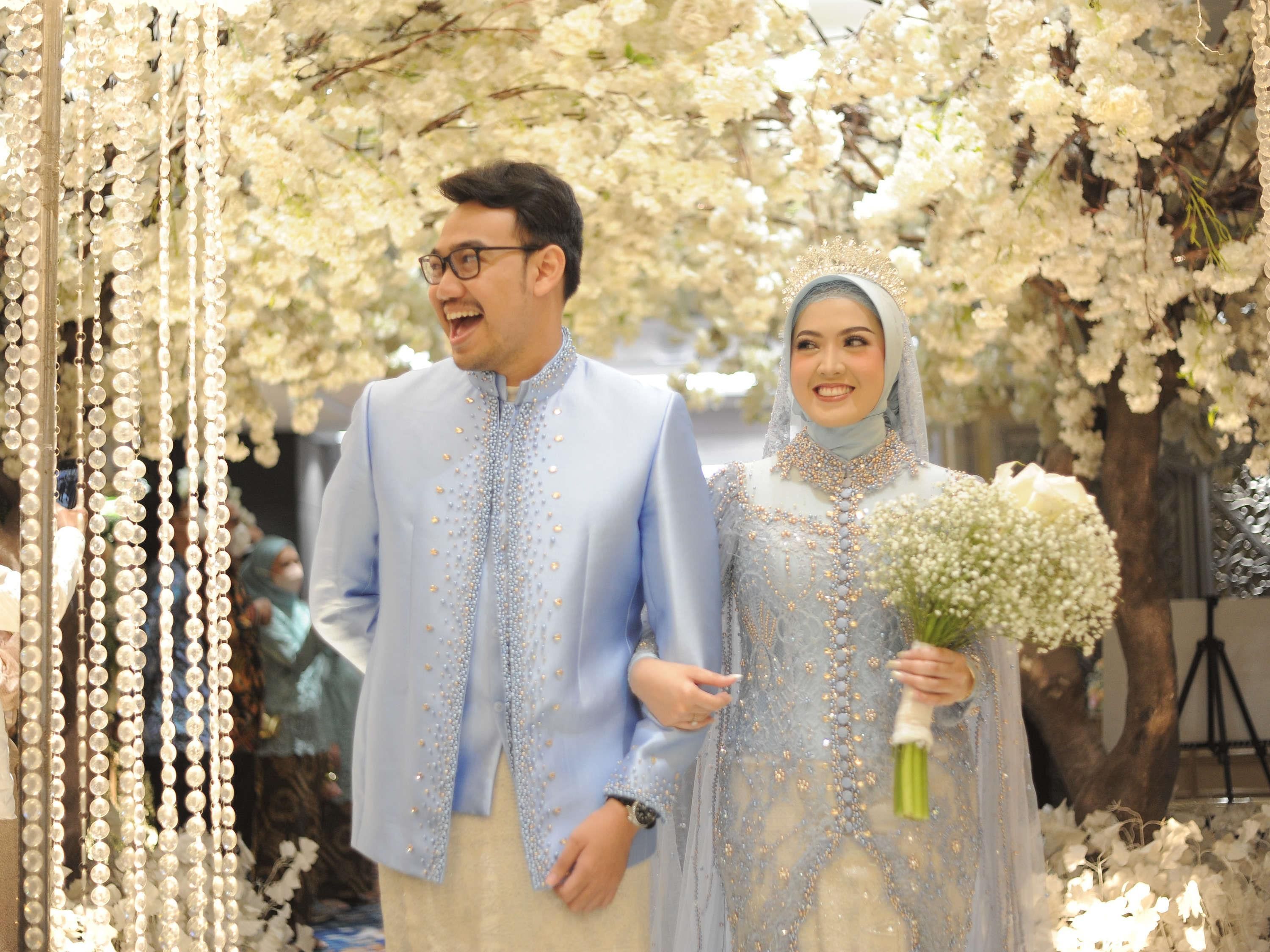 A couple walking under a floral archway.