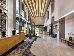 En modern hotellobby med en receptionsdisk, en sittgrupp och ett stort fönster.