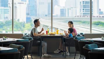 Un espace repas avec vue sur la ville, des tables avec des chaises et une grande fenêtre.