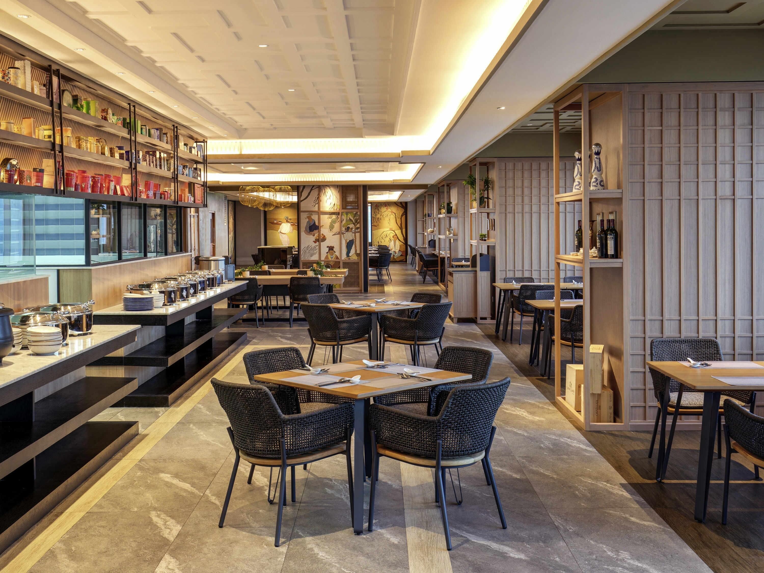 Um restaurante moderno com pé-alto, paredes de tijolo aparente e diversas opções de assentos, incluindo mesas e cadeiras.