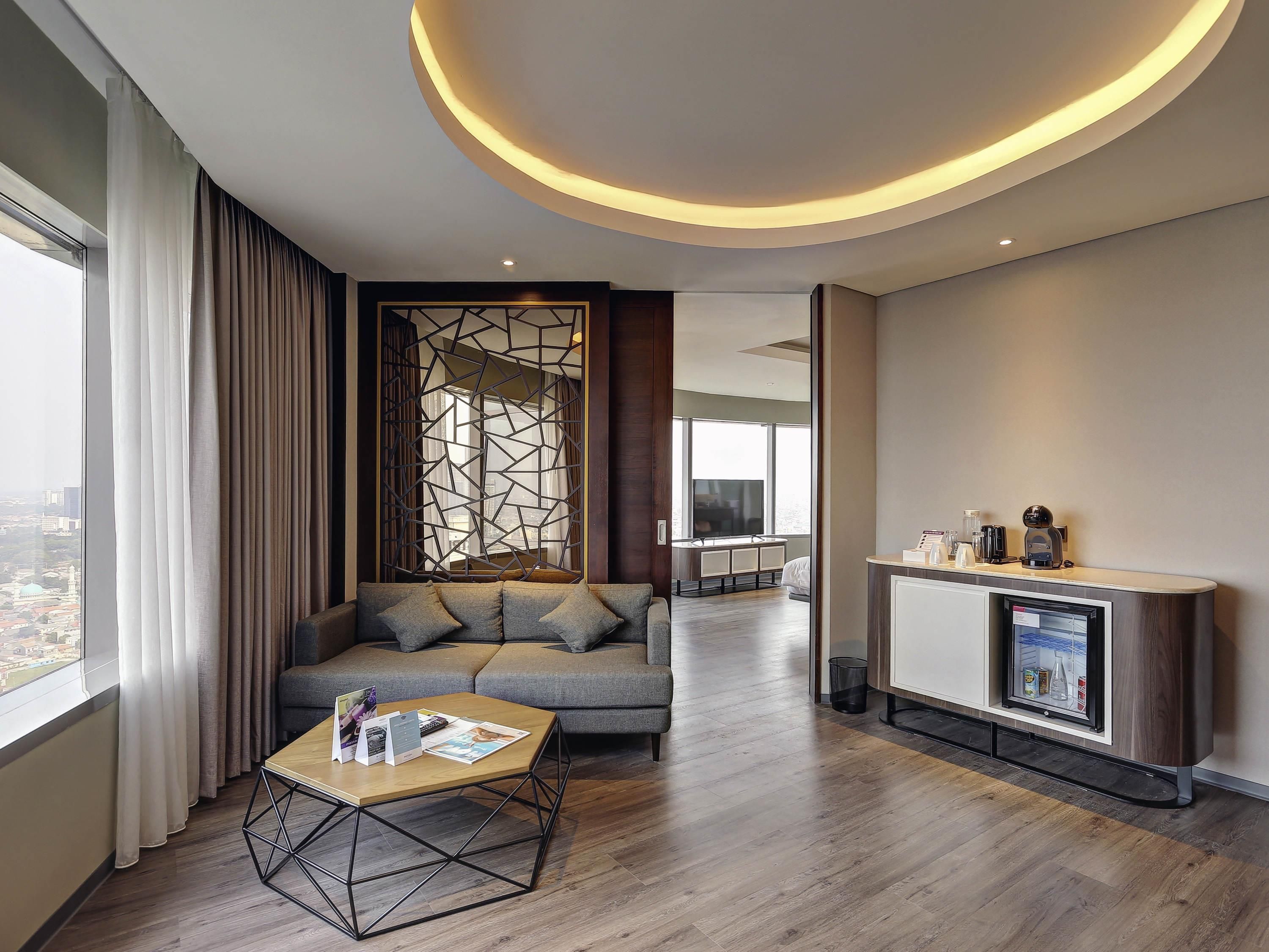 A modern hotel room with a sofa, coffee table, and a fireplace.