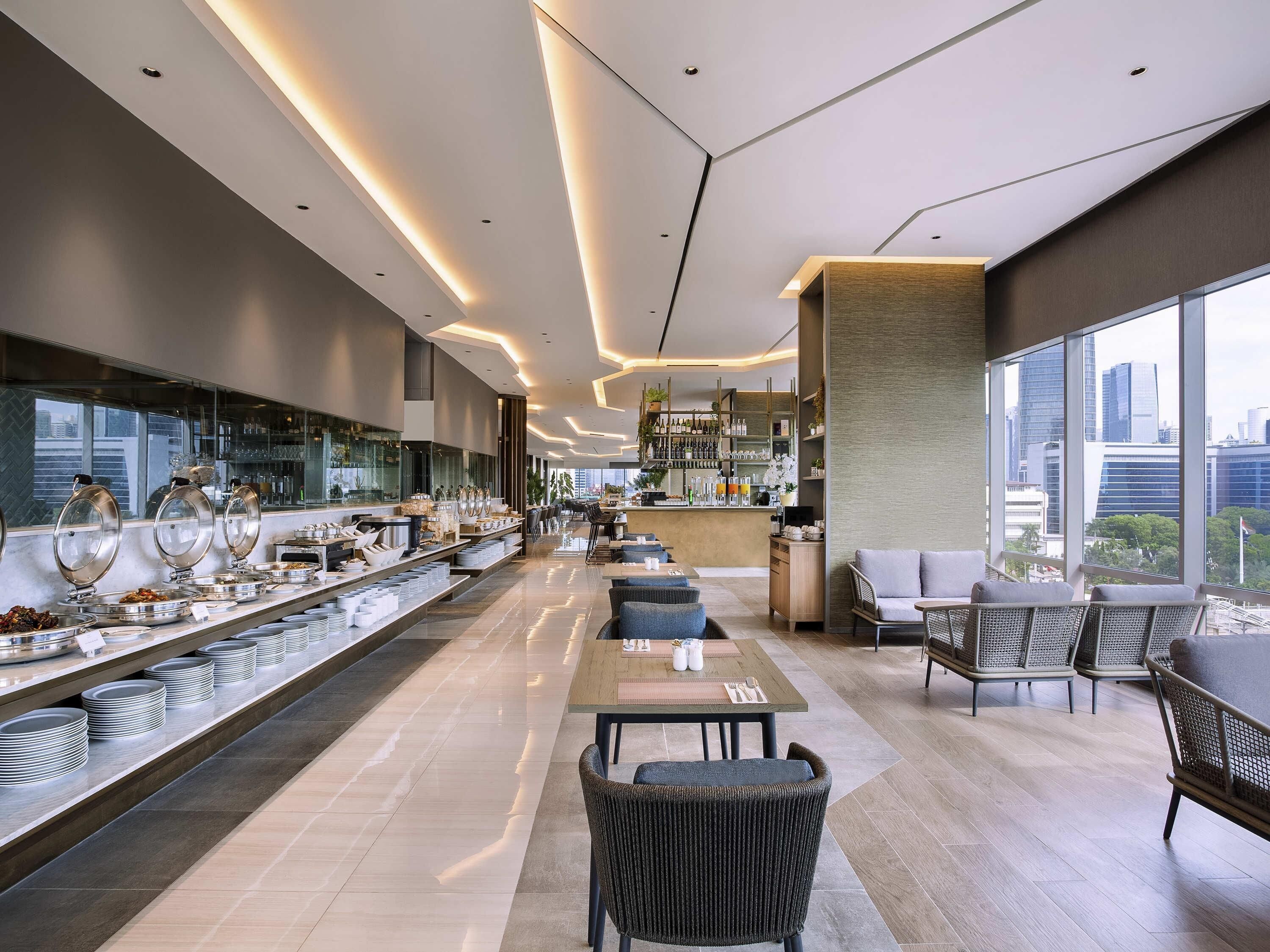 Un vestíbulo moderno de hotel con una larga recepción, zona de estar y un bar.