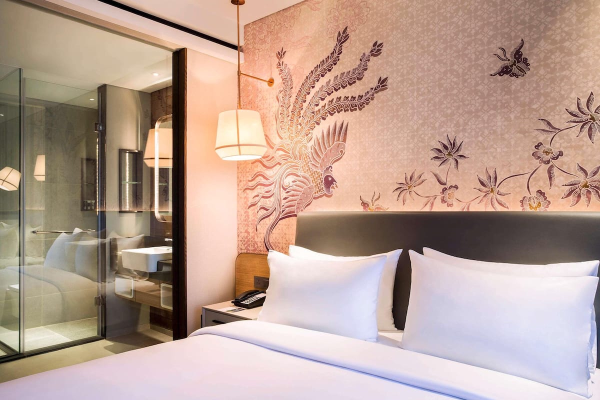 Ein Hotelzimmer mit einem Bett, einem Nachttisch, einem Telefon und einer Wand mit Blumenmuster-Tapete.