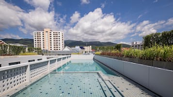 Una piscina con vistas a montañas y edificios al fondo.