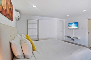 A hotel room with a bed, a television mounted on the wall, and a white wardrobe. - Prime Location: Spacious 4BR Home w/ Pool*Backyard (Noord)