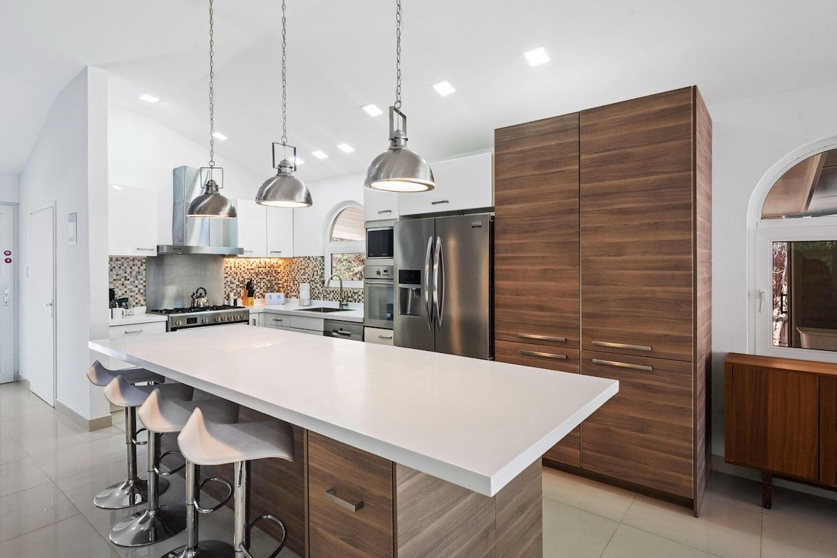 A modern kitchen with a central island, stainless steel appliances, and pendant lighting.