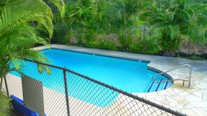 A swimming pool surrounded by lush greenery and stone tiles.