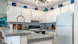 A modern kitchen with white cabinets, a black stove, and a white refrigerator.