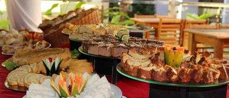 A buffet table with various desserts and a plate of white food garnished with fruit.