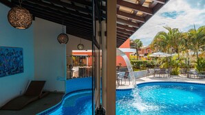 Una piscina con fuente, sillas de descanso y vista a un edificio de techo rojo.