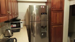 A stainless steel refrigerator with a water dispenser, a microwave, and a blender on the counter. - Apartamento Florangel (Santo Domingo Este)