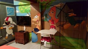 A children's playroom with cartoon-themed decorations, a small table, and a TV. - Apartamento Florangel (Santo Domingo Este)