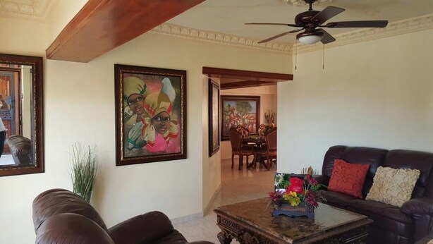 A living room with a sofa, coffee table, and paintings on the wall. - Apartamento Florangel (Santo Domingo Este)