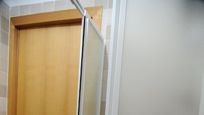 Una puerta de madera con un panel de vidrio, suelo de baldosas y pared blanca.
