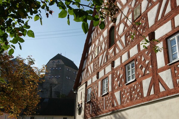 A half-timbered building with visible window frames and a stone tower in the background.