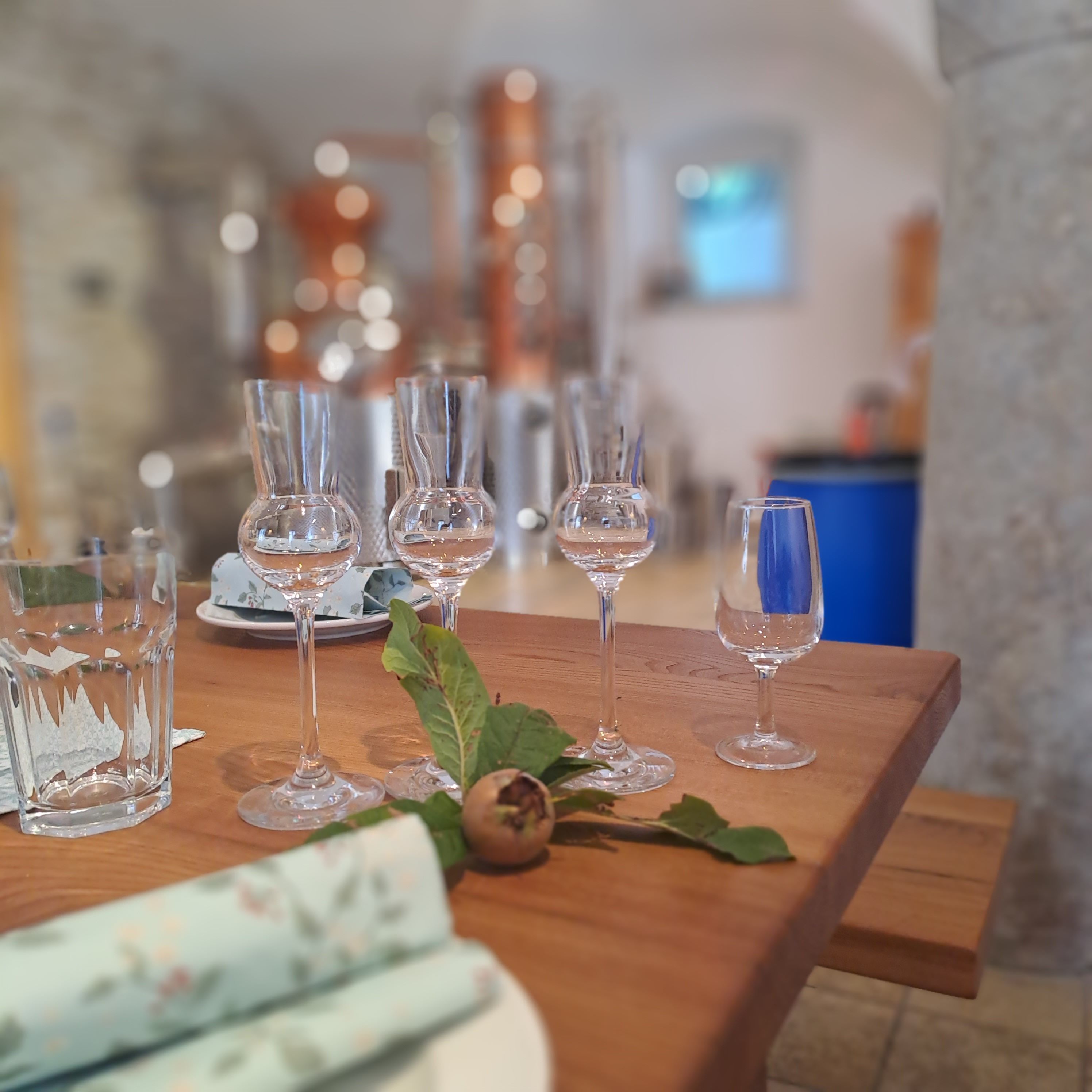 A table set with wine glasses and a decorative leaf centerpiece.
