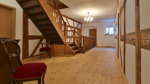 Un escalier en bois, un lustre, une chaise rouge et un plancher en bois.