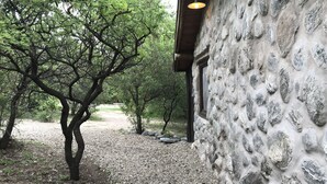 A stone building with a gravel path leading through a wooded area. - Cabanas Merlin (Merlo)
