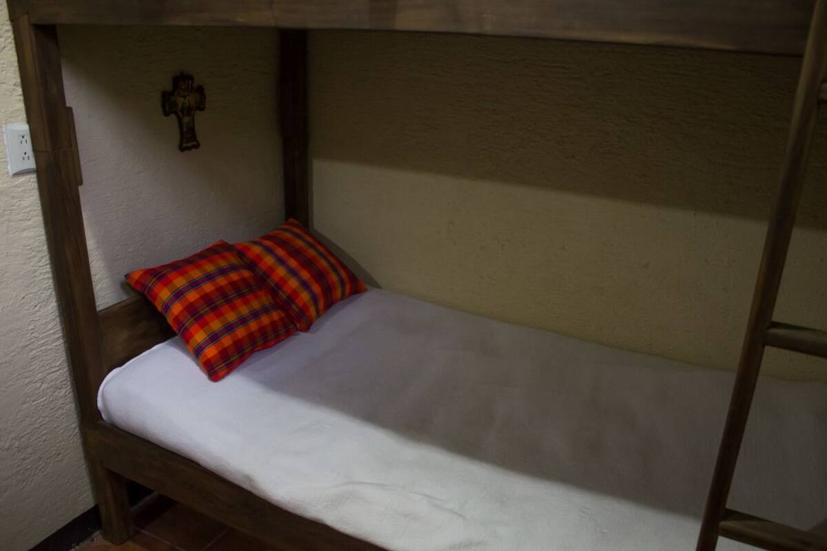 A bunk bed with a white mattress and a plaid pillow.