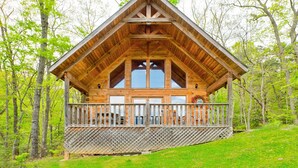 Una baita di legno con un balcone, immersa tra gli alberi.