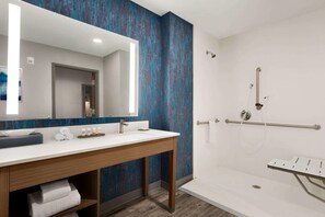 A modern bathroom with a large mirror, white sink, and a walk-in shower with a glass door. - La Quinta Inn & Suites by Wyndham Brunswick/Golden Isles (Brunswick)