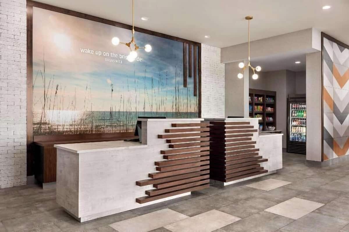 A reception desk with a modern design, a large wall mural, and a staircase leading to upper levels.