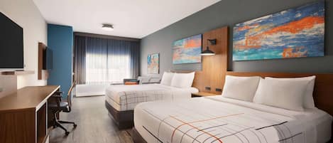 A modern hotel room with two beds, a desk, and a TV.