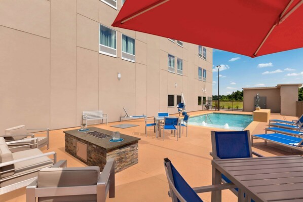 A poolside area with lounge chairs, a fire pit, and a swimming pool. - La Quinta Inn & Suites by Wyndham Brunswick/Golden Isles (Brunswick)