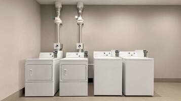 A laundry facility with four washing machines and two dryers, arranged in a row.