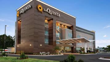A modern hotel with a prominent 'La Quinta' sign, a covered entrance, and a landscaped driveway.