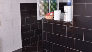 Een keuken met zwart-wit tegels, een raam met uitzicht en een hanglamp.