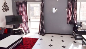 Een moderne woonkamer met een flatscreen televisie, een bank, een salontafel en een rood tapijt.