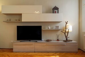 A modern living room with a flat-screen TV, built-in shelves, a decorative lamp, and a small statue.