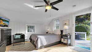 Une chambre à coucher comprenant un lit, une commode, une table de chevet, une lampe et un ventilateur de plafond.
