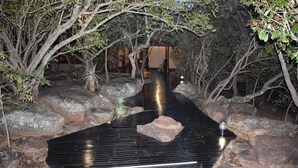 A pathway flanked by large rocks and trees, leading to a building with a traditional architectural style. - Sekala Private Game Lodge (Vaalwater)