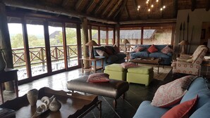 A spacious living area with a high ceiling, large windows, and a view of the outdoors. - Sekala Private Game Lodge (Vaalwater)