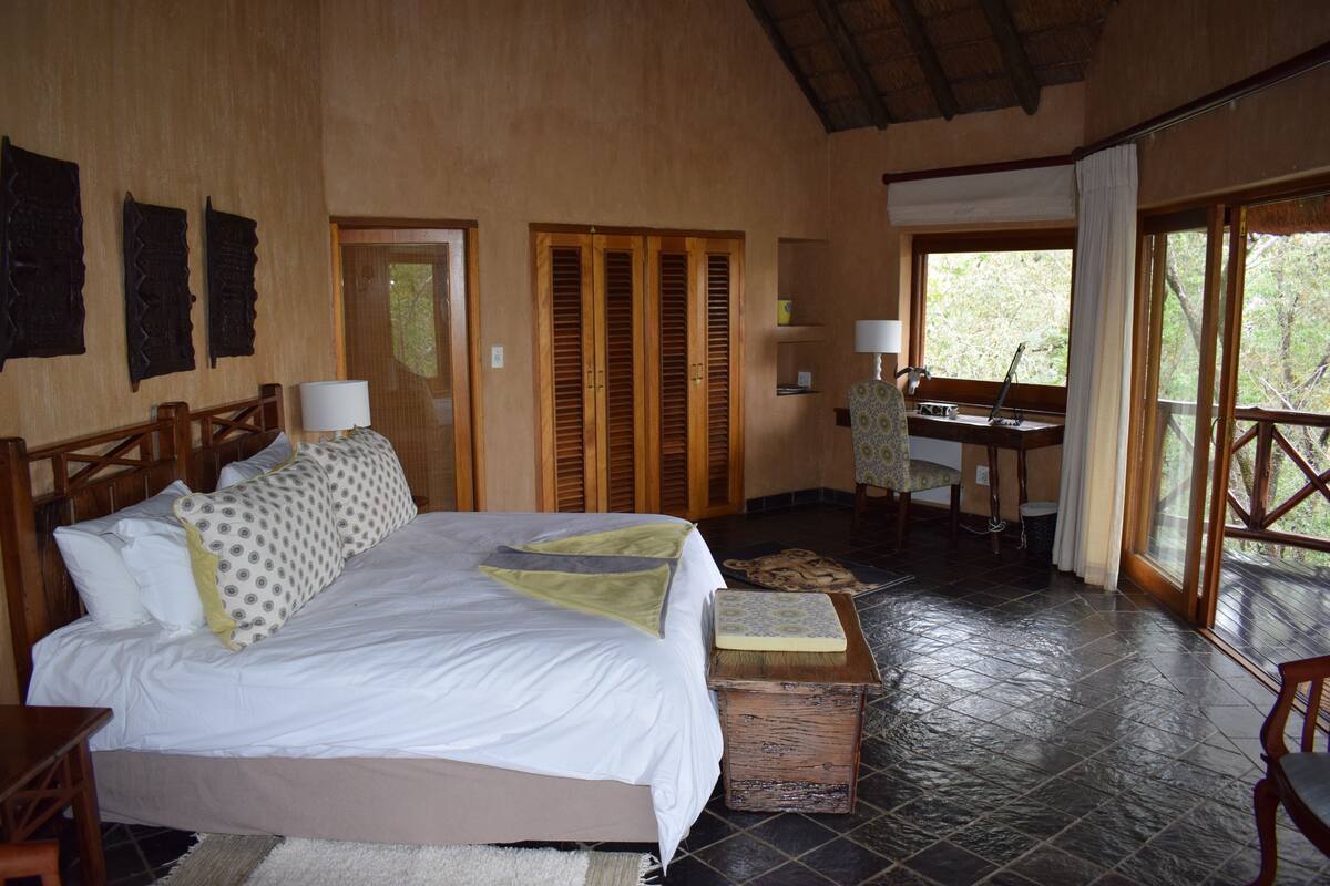 A bedroom with a large bed, wooden headboard, and a desk with a chair.