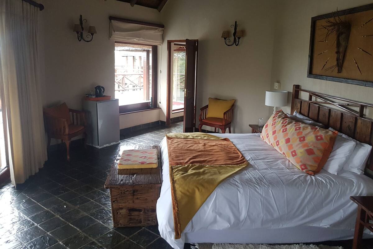 A bedroom with a bed, a wooden chest, a chair, a desk, and a window.