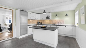 Una cucina moderna con mobili bianchi, un'isola con piano di lavoro nero e un forno a microonde.