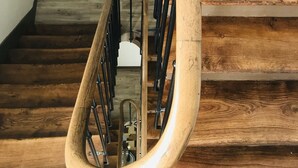 Eine Holztreppe mit Metallhandlauf und einem weißen Stuhl am Fuß.