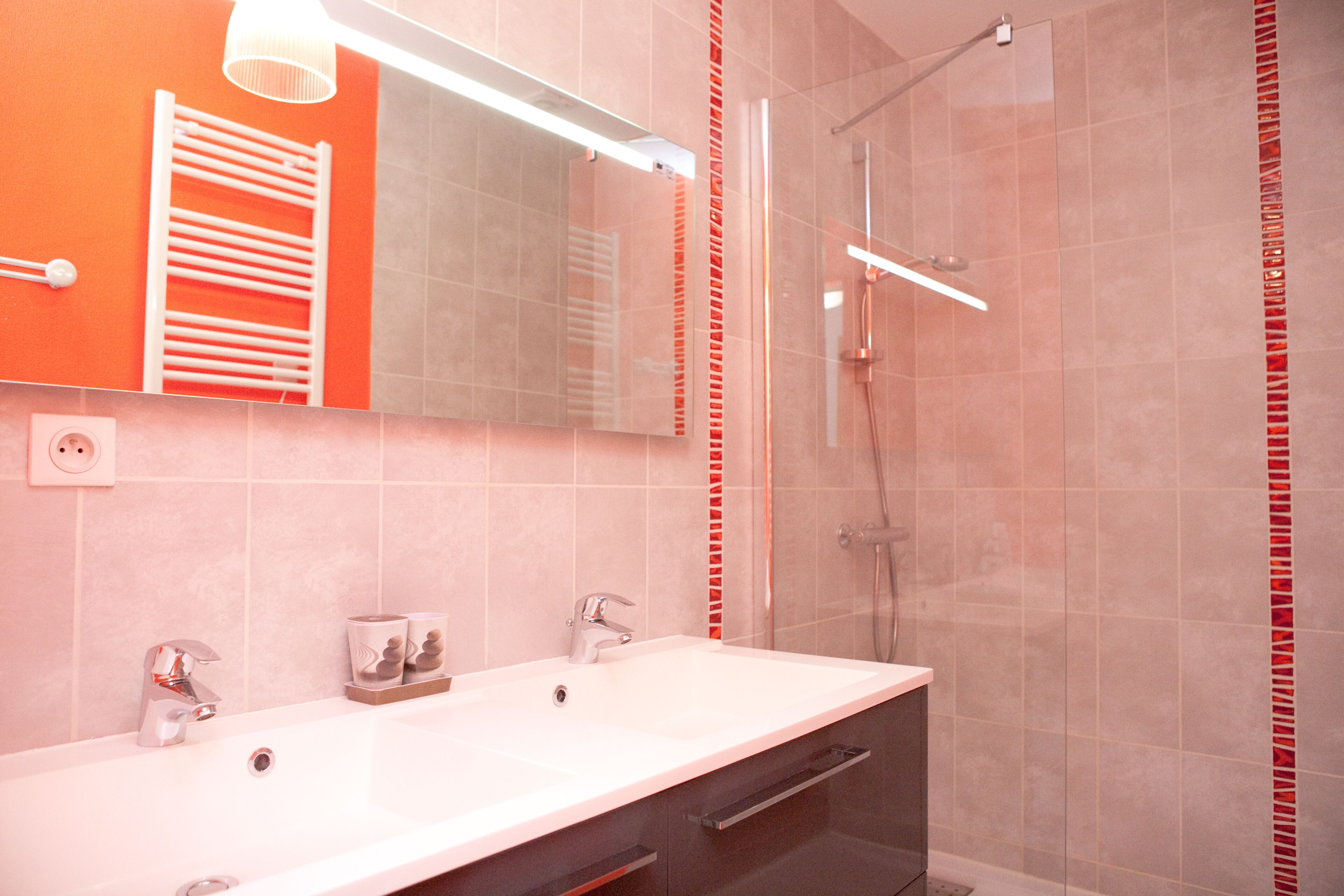 A bathroom with a white sink, two mirrors, a towel rack, and a shower area.