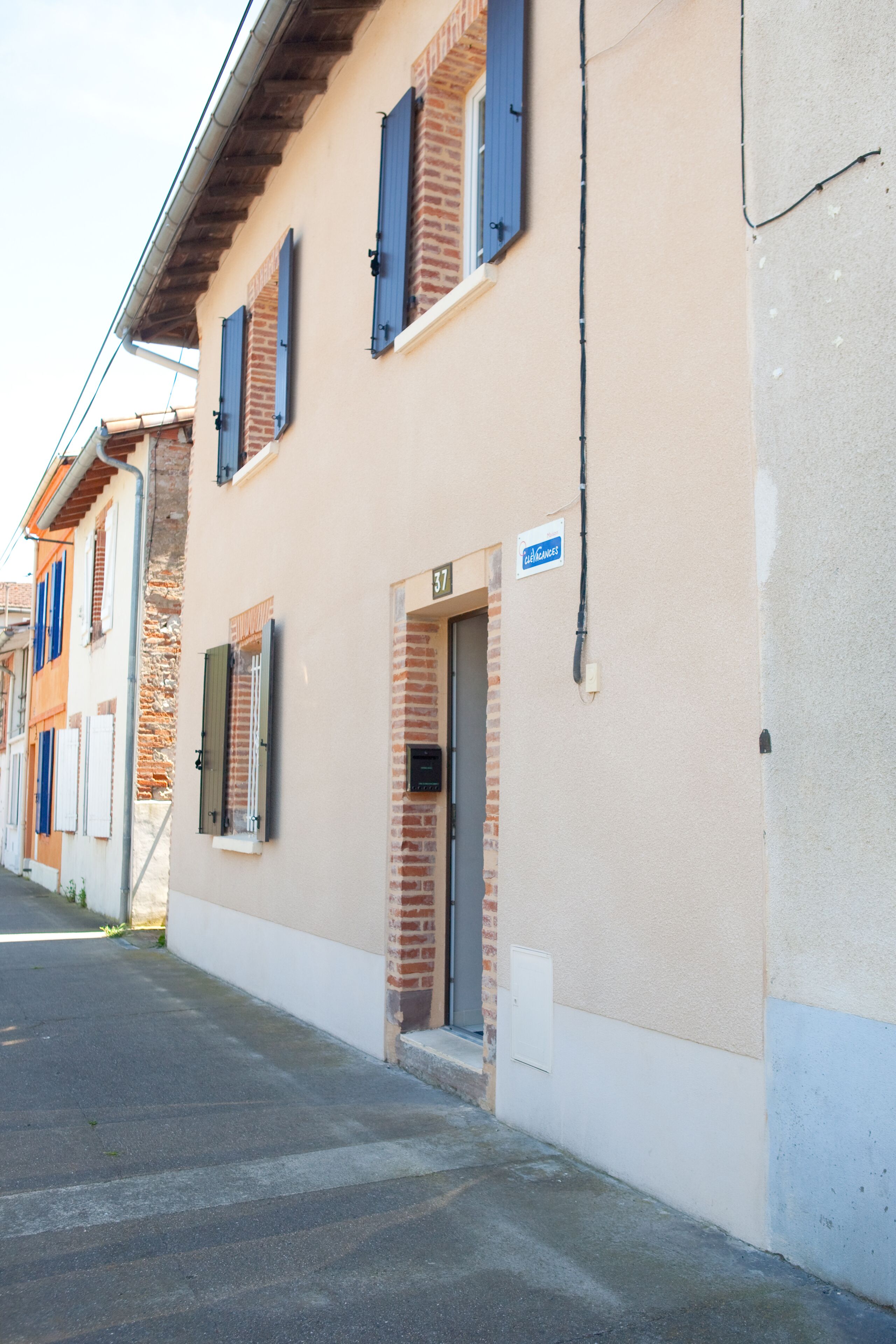 A building with a beige facade, a brick entrance, and a sign indicating it is a guesthouse.