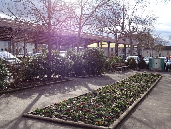 Ein Parkplatz mit einer Reihe geparkter Autos, einer Bank und einem Blumenbeet.