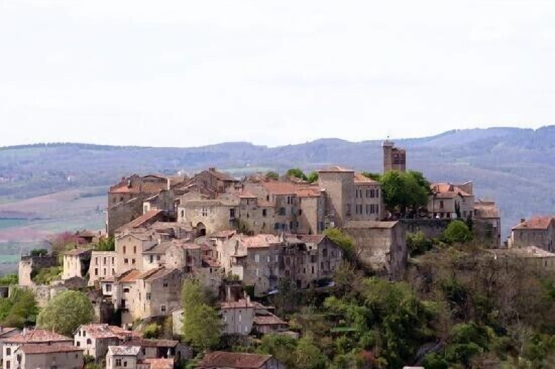 Une ville historique aux bâtiments en pierre, regroupés sur une colline, qui surplombe une vallée.