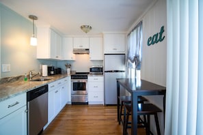 Compact kitchen with appliances, sink, and dining area.